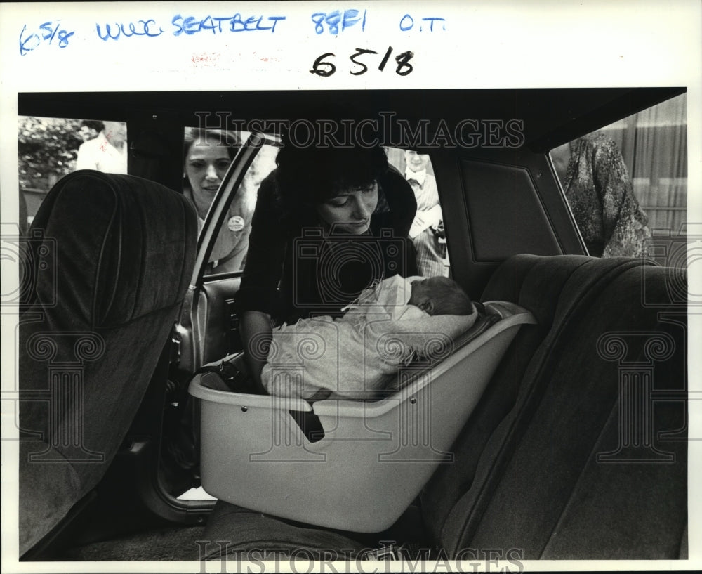 1984 Press Photo Automobile seats: Baby, Janice Rish puts Newborn in carseat. - Historic Images