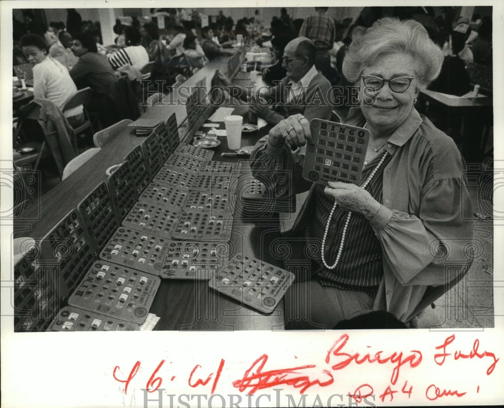 Bingo player, Rosemary Ford, shows card at Lions Enterprises Hall - Historic Images