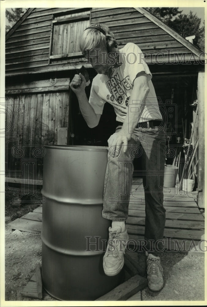 1992 Press Photo Carl Chase hammers on a 55-gallon steel drum at Maine workshop. - Historic Images