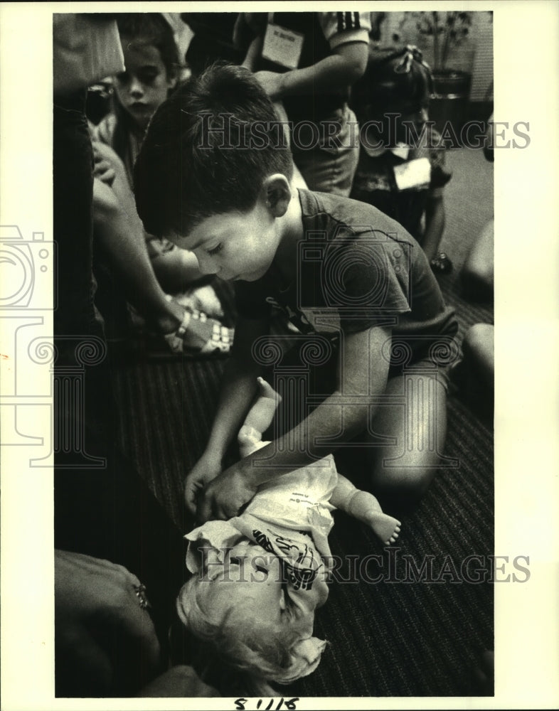 1984 Press Photo Chris diapers a doll, learning how to diaper a baby. - Historic Images