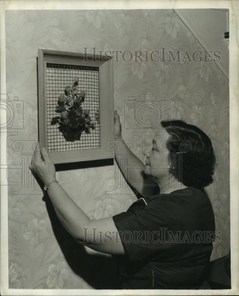 1957 Press Photo Mrs. Fred Doadier Hanging a Shadowbox Plaque On the Wall - Historic Images