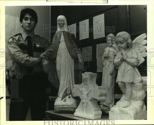 1989 Press Photo Deputy Curtis Doss poses with statues found on Davis Landing. - Historic Images