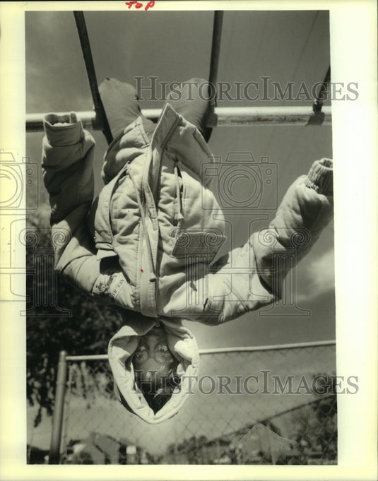 1989 Press Photo Kelly Ecuyer hangs on monkey bars during recess at St. Clement - Historic Images