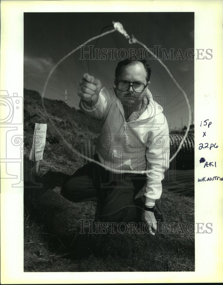 1994 Press Photo Greg du Tyreil kneels next to nutria burrow with a snare - Historic Images