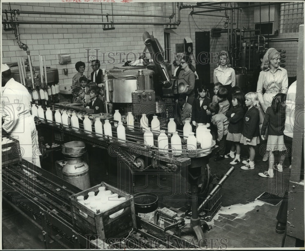 1969 Children watch bottles filled with milk at center of gutter - Historic Images