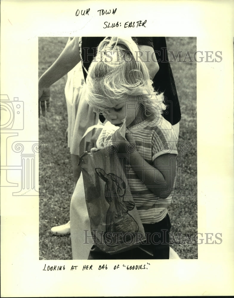 1985 Press Photo Lafreniere Park Easter egg hunter looks at her bags of goodies - Historic Images