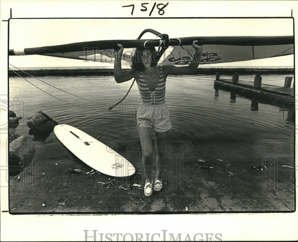 1984 Press Photo Ellen Eagan carries sail of windsurfer from Lake Pontchartrain. - Historic Images