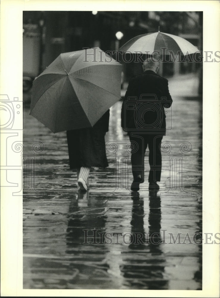 1990 Press Photo Elderly couple in the wet walkway along Jackson Square - Historic Images