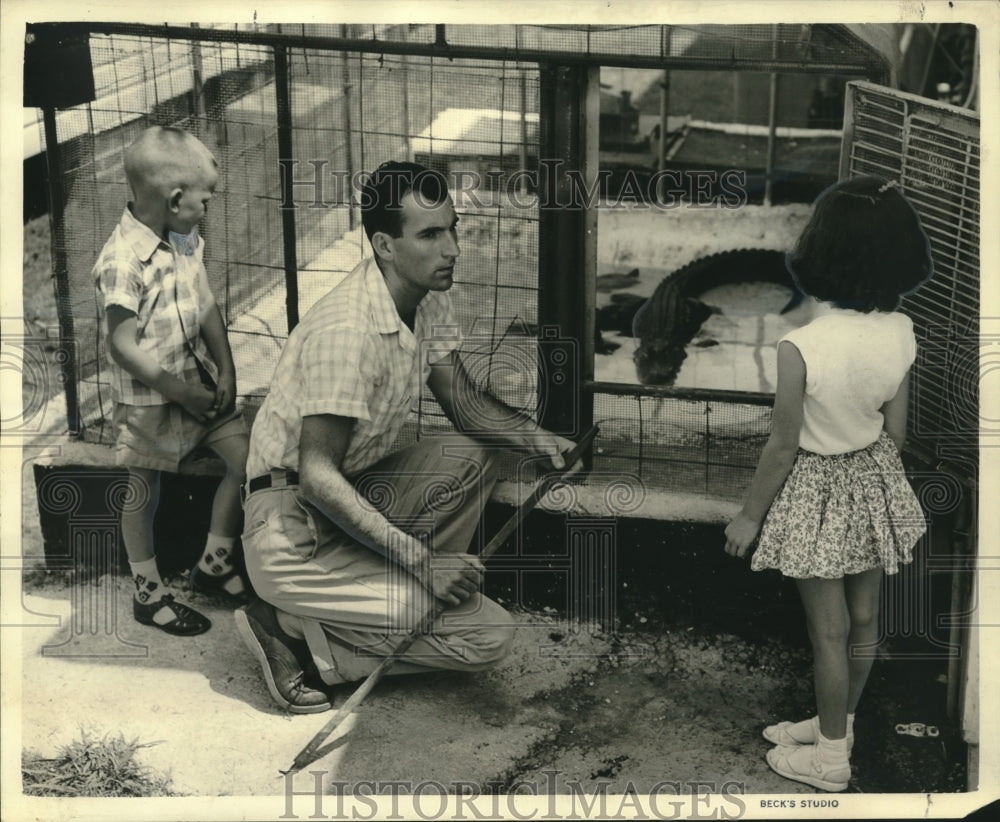 1959 Press Photo Tom, the alligator, lazily suns himself as Janet Falcon watches - Historic Images