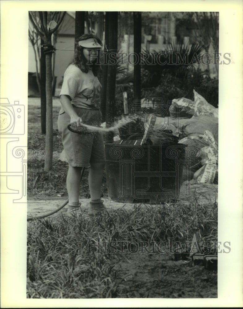 1989 Press Photo Karen Foley waters trees at Woldenberg Park near the Aquarium. - Historic Images