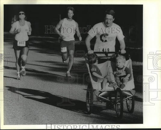 1990 Press Photo Paul Flanagan pushes sons in Mandeville's Centennial Run. - Historic Images