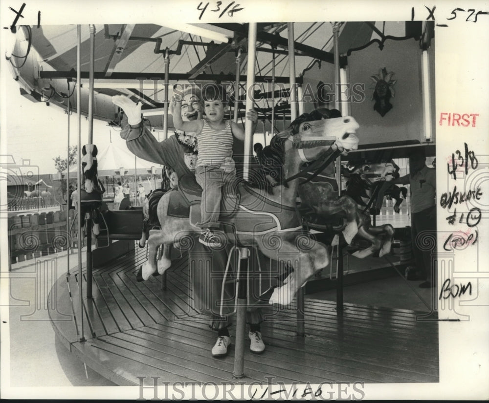 1977 Youngster &amp; clown rides merry-go-round at Elmwood Kiddie Land - Historic Images