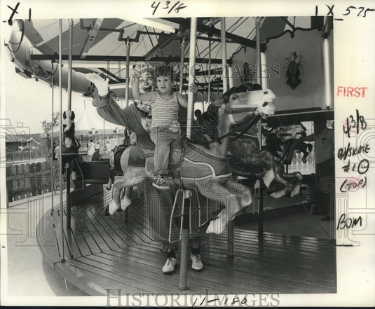 1977 Youngster & clown rides merry-go-round at Elmwood Kiddie Land - Historic Images