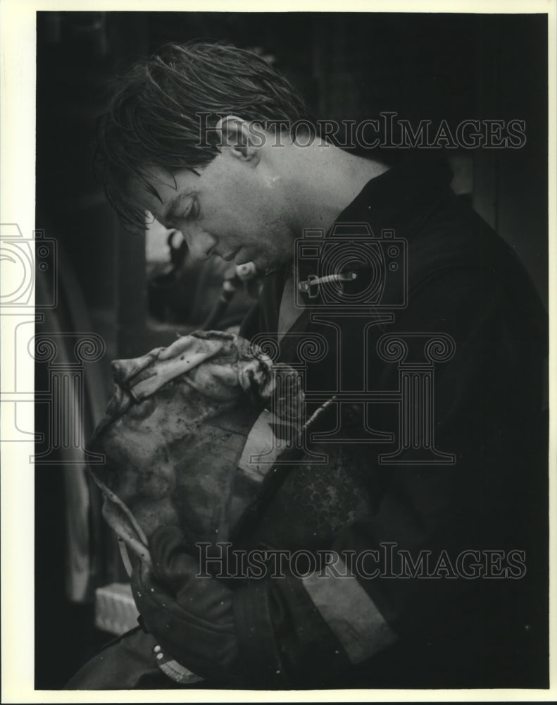 1988 Press Photo Fire fighter Numa Jone looks at what is left of his helmet - Historic Images