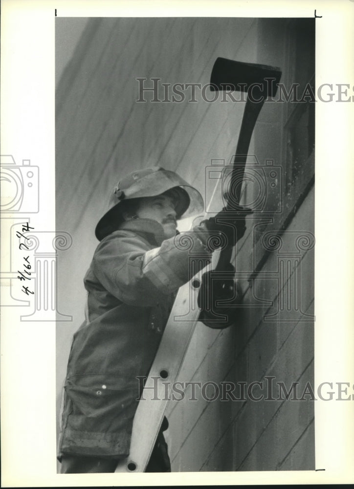 1991 Press Photo New Orleans firefighter breaks open window at warehouse - Historic Images