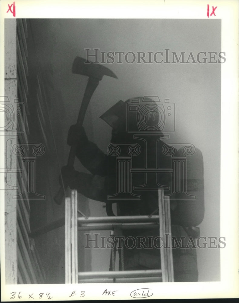 1990 Press Photo Firefighter breaks a window with ax in smoke-filled building - Historic Images