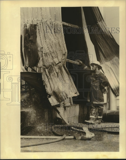 1989 Press Photo Firefighter J. Mathews examines damage to a warehouse. - Historic Images