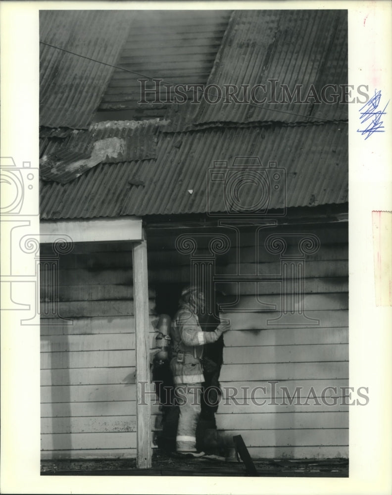 1991 Press Photo  Kenner Volunteer firefighter examines fire damaged house - Historic Images