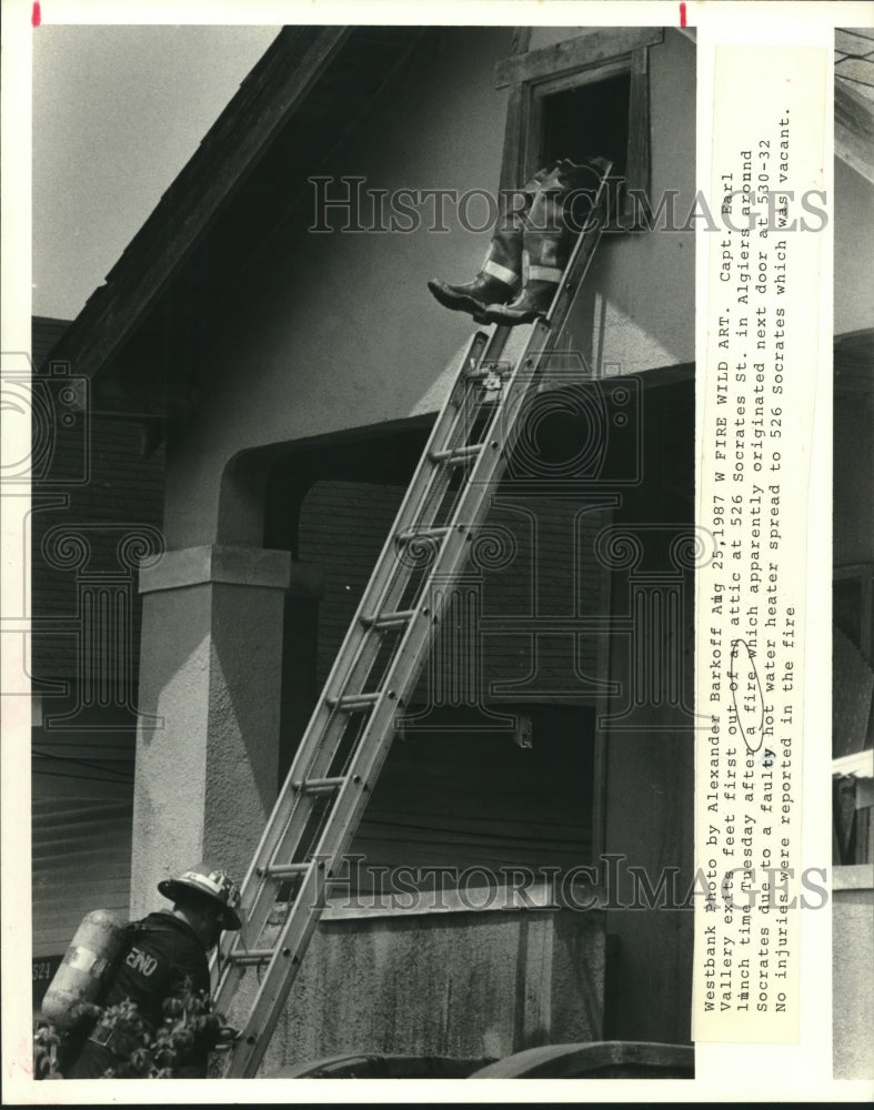 1987 Press Photo Captain Earl Vallery exits attic feet first at 526 Socrates St. - Historic Images