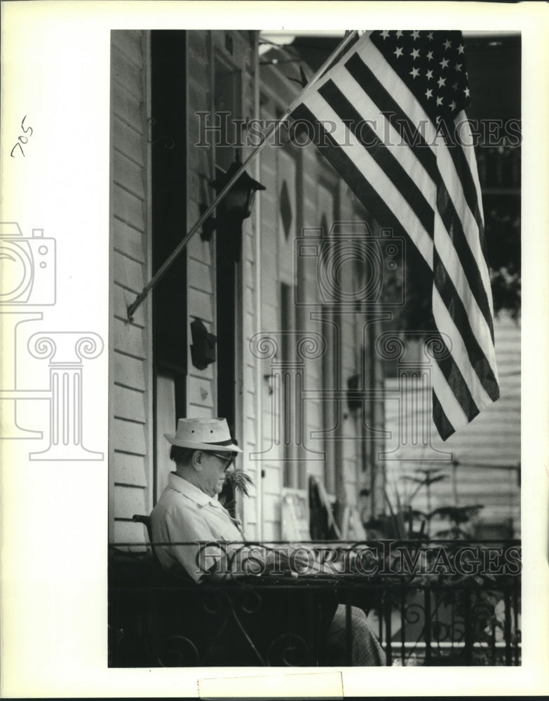 1988 Press Photo M.B. Gaubert under his American flag reading on his front porch - Historic Images