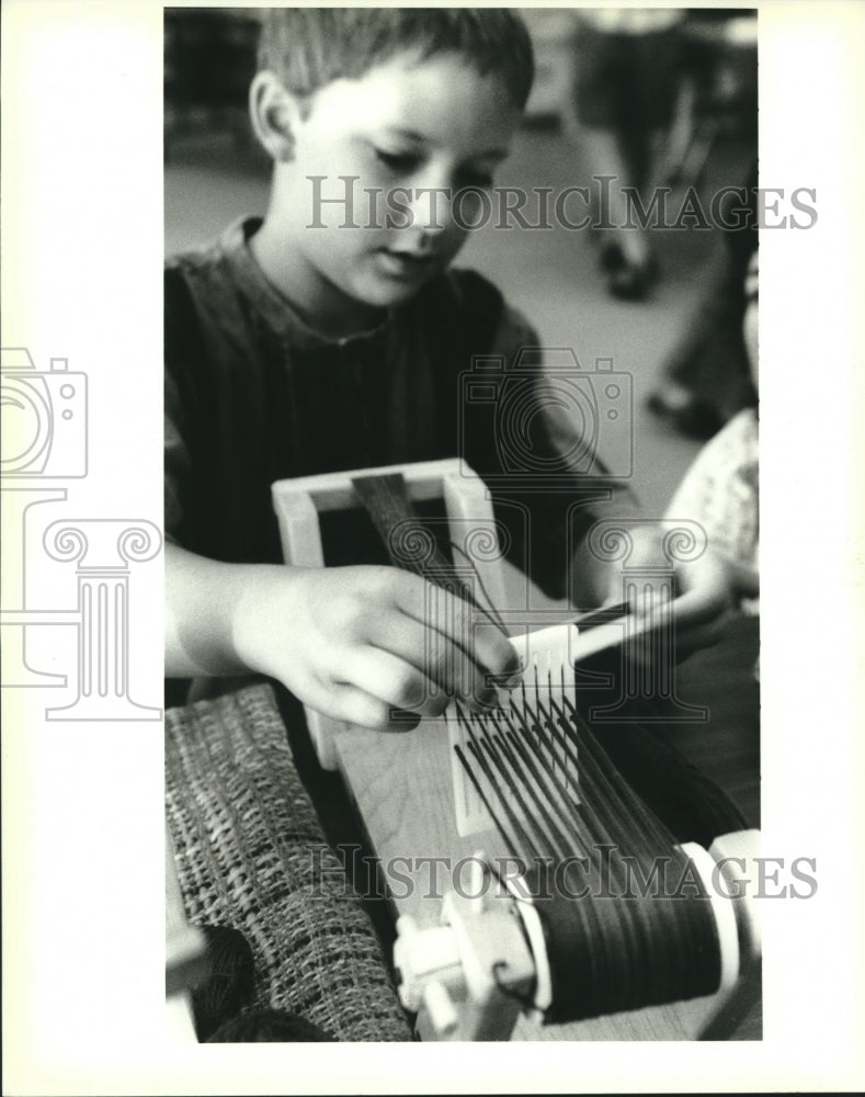 1995 Press Photo Tristam Schalona makes a book mark on a rigid needle belt loom - Historic Images