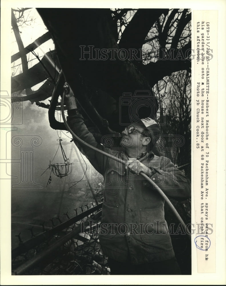 1985 Press Photo Robert Reboche sprays garden hose on a house fire next door - Historic Images