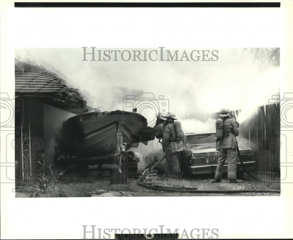 1991 Press Photo Firemen spray car and boat involved in house fire. - Historic Images