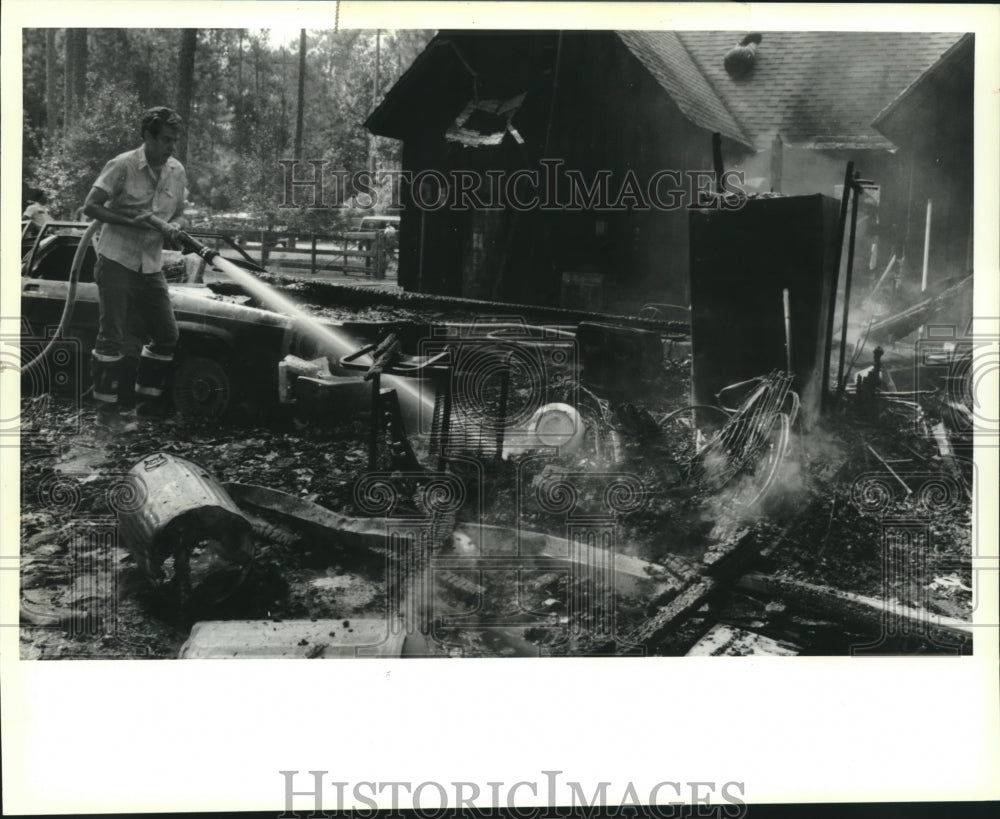 1990 Press Photo Lacombe firefighter Jack Ramierz hoses smoldering fire remains - Historic Images