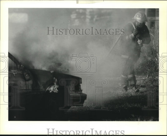1990 Press Photo New Orleans firefighter Kenneth Hall battles a car fire on I-10 - Historic Images