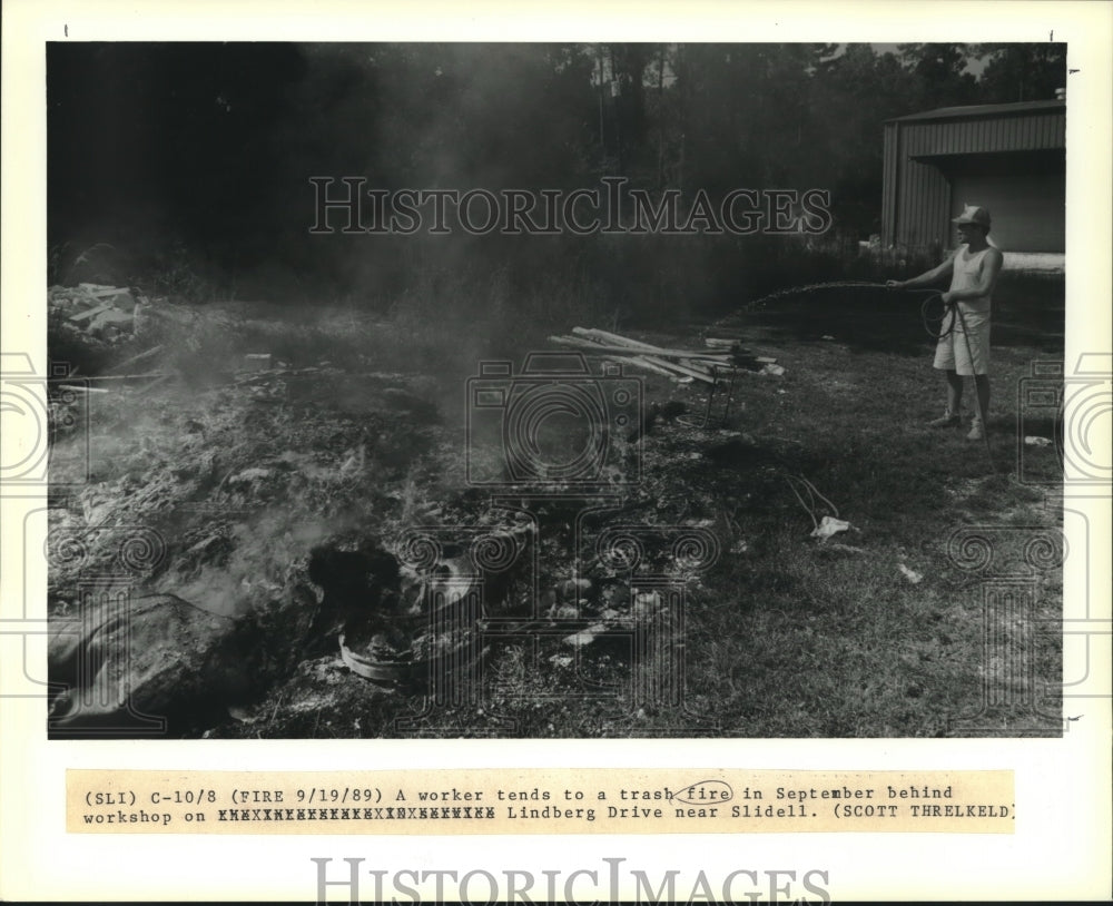 1989 Press Photo A worker tends to a trash fire behind his workshop near Slidell - Historic Images