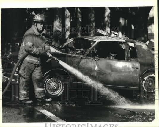 1995 Press Photo Firefighter hoses street from fiery car wreck. - nob10783 - Historic Images