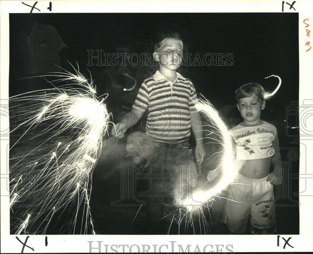 1988 Press Photo Gary and Danny Nehlig have fun with sparklers at Parc Chenier - Historic Images