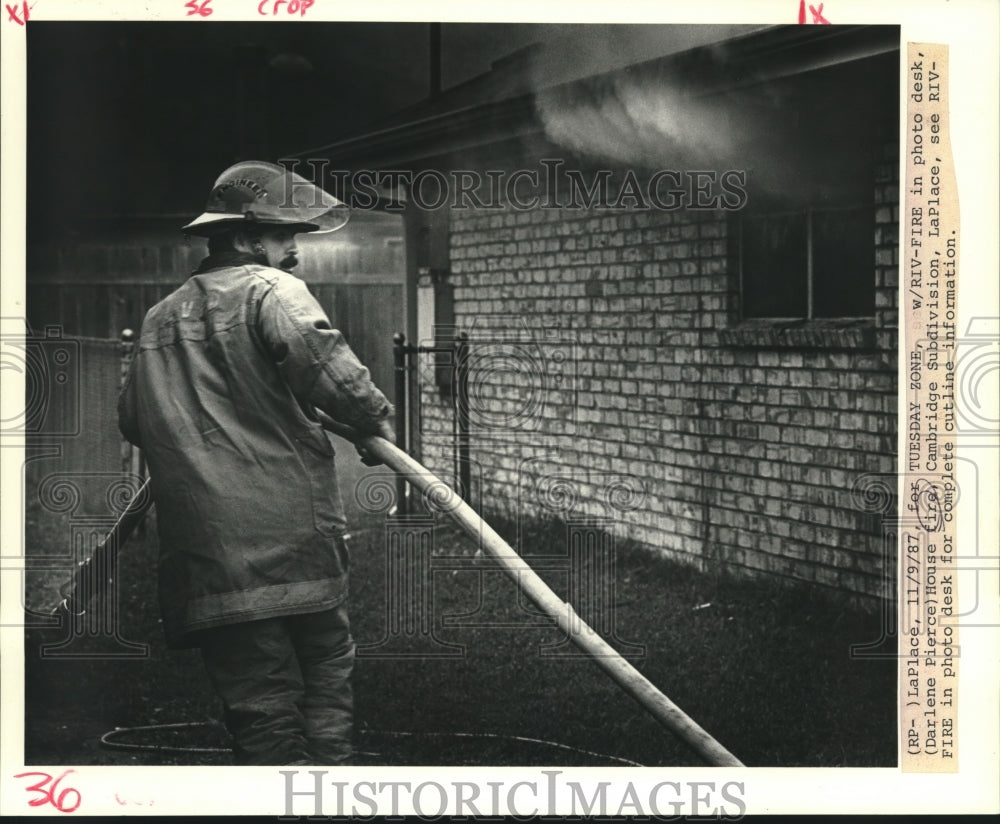 1987 Press Photo Fireman puts out house fire at Cambridge Subdivision in LaPlace - Historic Images