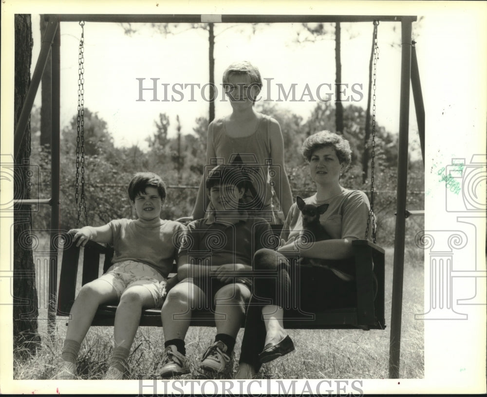 1989 Press Photo Bryan Fisher relaxes with his family in yard swing. - Historic Images