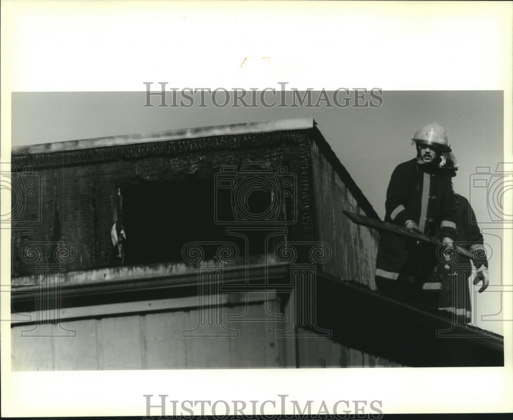 1988 Press Photo Kenner Firefighter Sid Deleon works on roof after fire - Historic Images