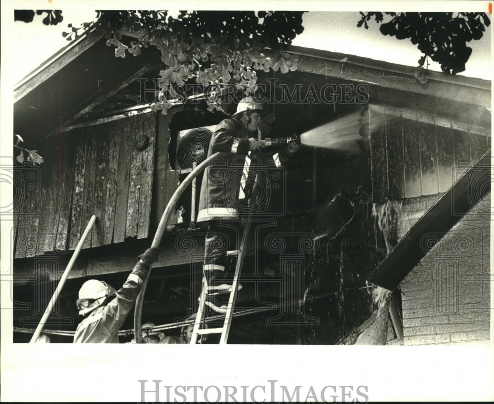 1987 Press Photo Firefighter Ralph Hardy III hoses down attic fire, Metairie - Historic Images