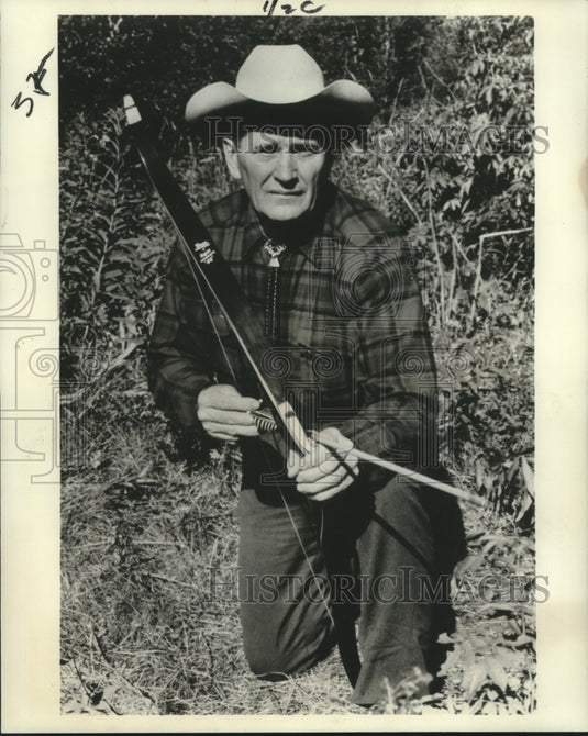 1966 Press Photo Joe Foss kneels with bow and arrow waiting for his prey. - Historic Images