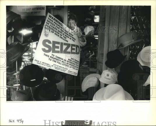1989 Press Photo Gary Quaintance places Seized sign in "Foxie, The Hatter" store - Historic Images