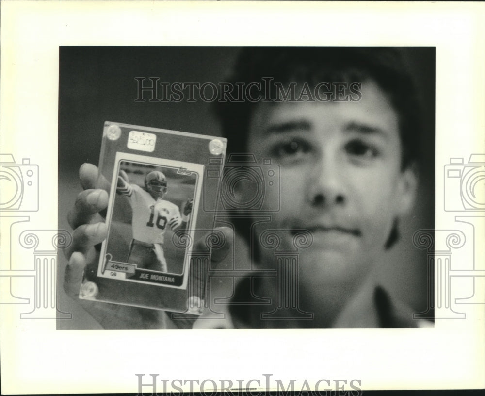 1990 Press Photo Football - Allen Gautreaux holds a Joe Montana football card - Historic Images