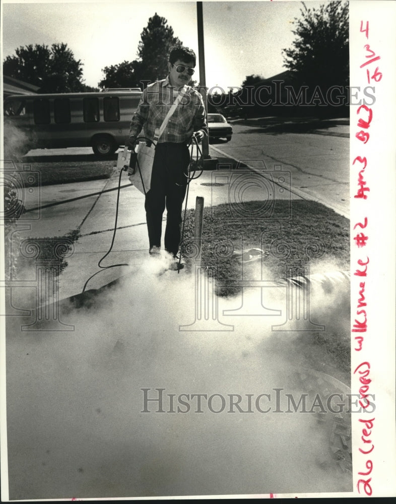 1987 Press Photo City worker checks smoking manhole for cracks and broken lines - Historic Images