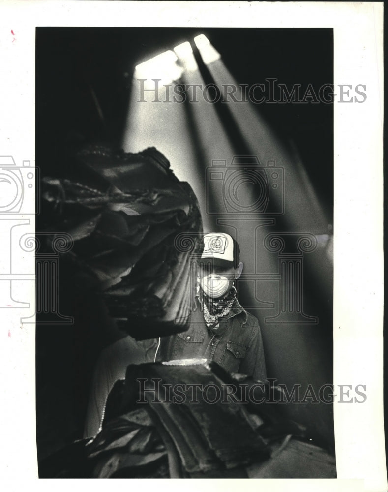 1986 Press Photo Worker piles wet cardboard after warehouse fire, Gentily - Historic Images