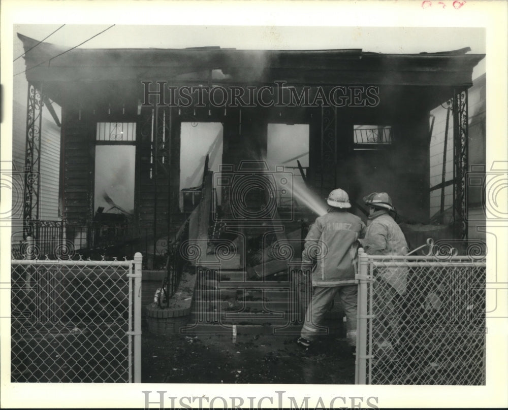 1989 Press Photo New Orleans firemen hose down the shell of a house. - Historic Images