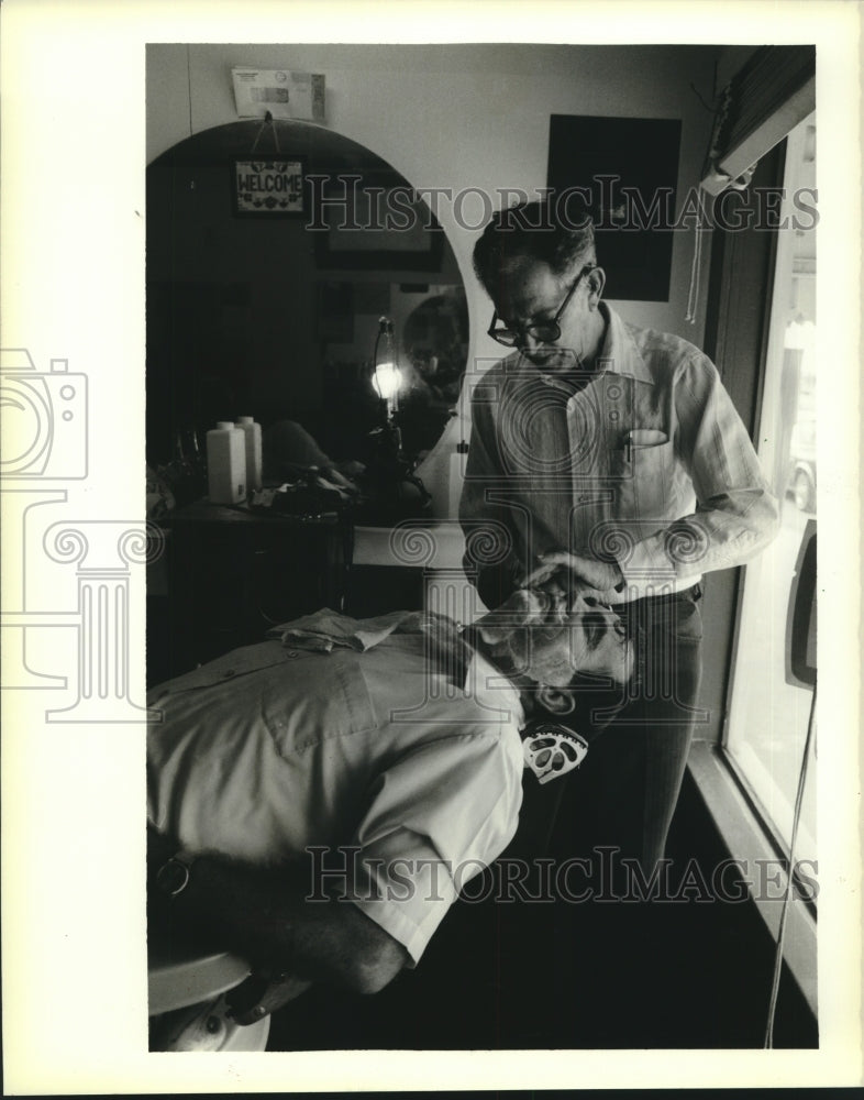 1988 Press Photo Barber Avie Fusilier shaves a customer in downtown Mamou - Historic Images