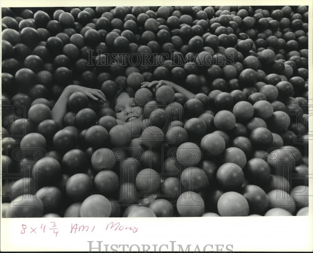 1989 Press Photo Little girl covered up with balls at Space Walk Fun Factory - Historic Images