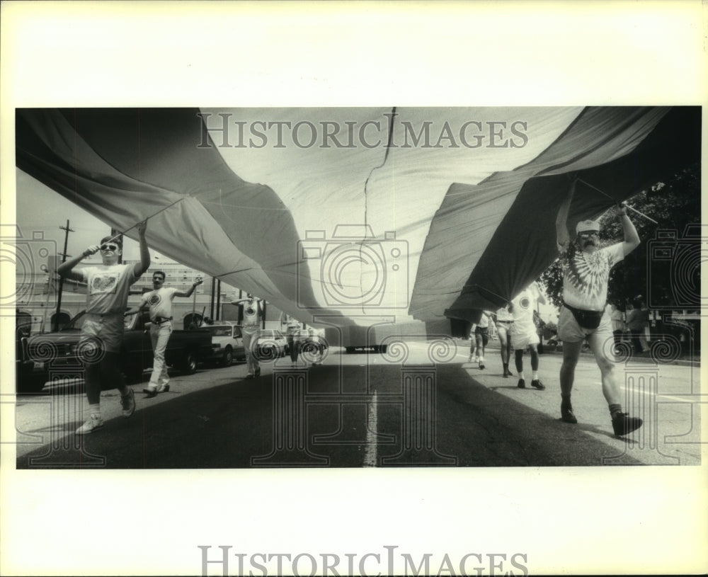 1991 Press Photo Marchers in the Gay Pride Parade carry a rainbow colored flag. - Historic Images