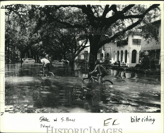 1991 Press Photo Pair of youths biking on flooded streets on Palmer & Prieur St. - Historic Images