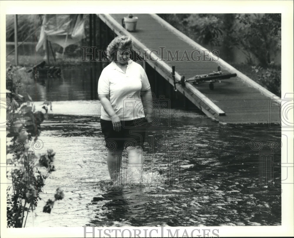 1991 Press Photo Kathleen Alphonso walks in flooded waters in front of her house - Historic Images