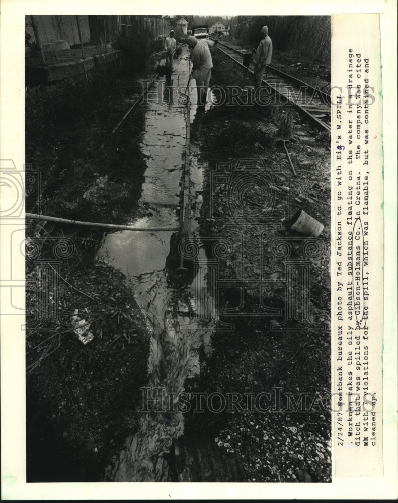 1987 Press Photo Workman rakes up spill in drainage ditch, Gretna - nob20570 - Historic Images