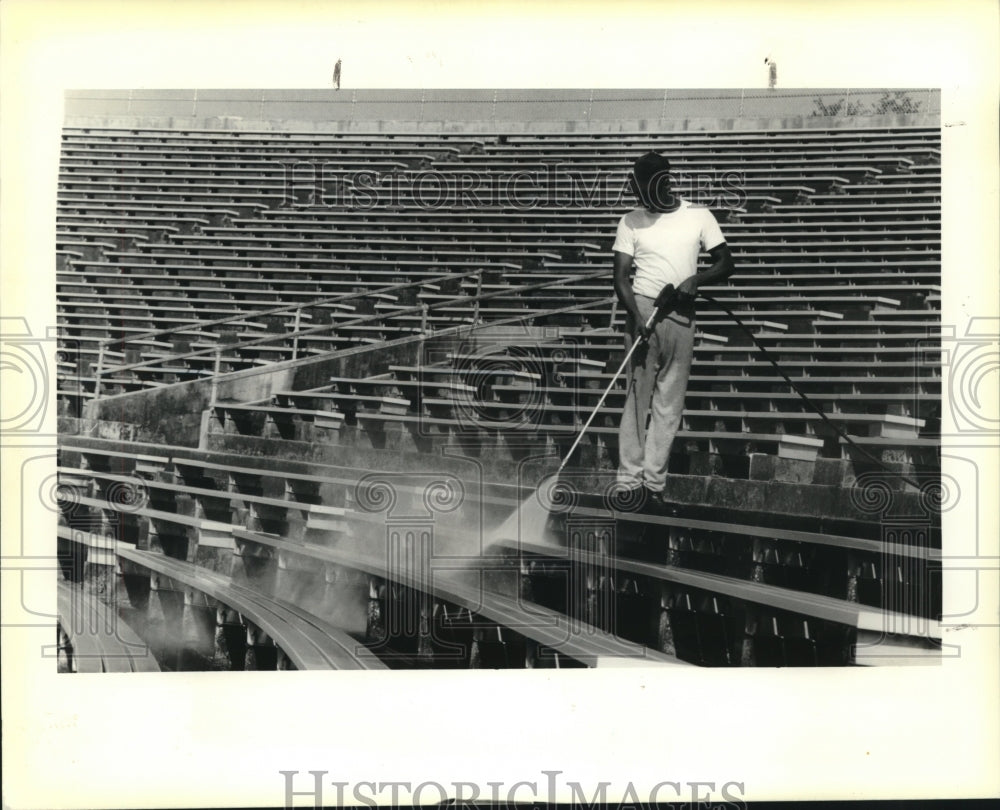 1990 Press Photo Worker cleans Tad Gormley Stadium seats with water hose-Historic Images