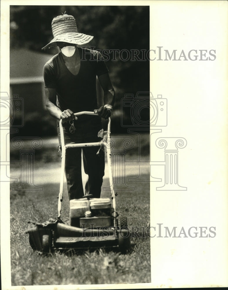 1988 Press Photo Willard Richardson cuts grass with big sun hat and mask - Historic Images